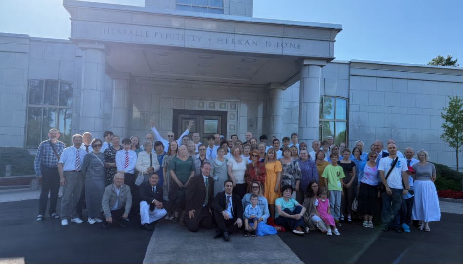 100 membros do Distrito posando para foto em frente ao templo